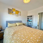 Modern bedroom with geometric bedspread and wall art.