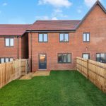 Modern brick house with garden and wooden fence.