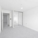 Minimalist white room with mirrored wardrobe doors.
