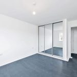 Minimalist empty room with mirror wardrobe and door.