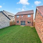 New brick house with garden and blue sky.
