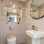 Modern bathroom with mirror, sink, and toilet.