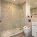 Modern bathroom with glass shower and vanity unit.