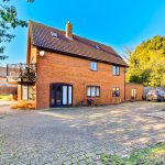 Spacious brick house with car park and trees.