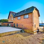Three-storey brick house with fenced garden area.