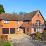 Large red brick house with garage and balcony.