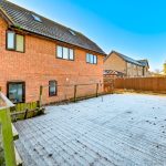 Backyard with frosty wooden deck and brick house.
