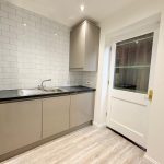 Modern kitchen with white tiles and grey cabinets.