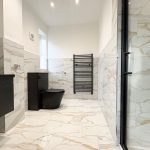 Modern bathroom with black fixtures and marble tiles.