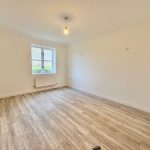 Empty room with wooden flooring and window.