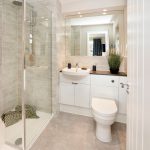 Modern bathroom with shower, sink, toilet and mirror.