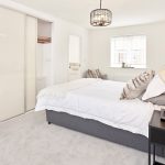 Modern bedroom with grey bed and white decor.