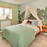 Children's bedroom with treehouse wallpaper and canopy bed.