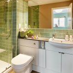 Modern bathroom with glass shower and green tiles.