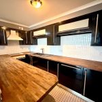 Modern kitchen with wooden countertops and black cabinets.