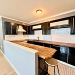Modern kitchen with black cabinets and wooden countertop.