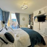 Modern bedroom with double bed and wall-mounted TV.