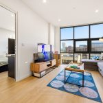 Modern living room with large windows and TV.