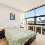 Modern bedroom with large window and wall art.