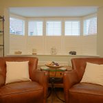 Cosy seating area with leather chairs and bay window.