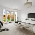Modern living room with garden view through glass doors.