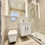 Modern bathroom with shower, toilet, and vanity unit.