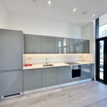 Modern kitchen with grey cabinets and large window.