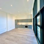 Modern kitchen with large windows and wood floor.