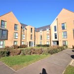 Modern brick apartment building with green windows.