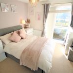 Bright bedroom with cosy decor and window view.