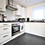 Modern kitchen with white cabinets and appliances.