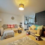 Cosy living room with sofas and kitchen view.