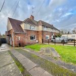 Semi-detached house with driveway and parked cars.