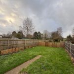 Back garden with grass and wooden fence.