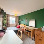 Cosy bedroom with green accent wall and desk.