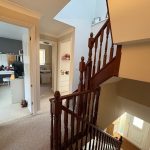 Spacious hallway with wooden staircase and open doors.