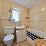 Bright bathroom with bath, sink, and toilet.