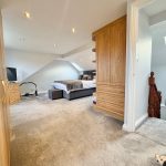 Spacious attic bedroom with skylight and wooden wardrobe.