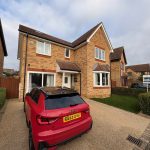 Brick house with red car parked outside