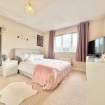 Cosy bedroom with pink decor and large window.