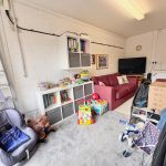 Cosy room with toys, sofa, shelves and TV.