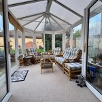 Bright conservatory with wicker furniture and large windows.