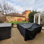 Patio with covered furniture and garden view.