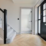 Modern hallway with staircase and black door
