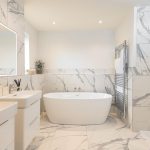 Modern bathroom with marble tiles and freestanding bathtub.