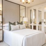 Modern bedroom with mirrored wardrobe and bedside lamps.