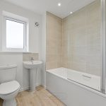 Modern bathroom with toilet, sink, bathtub, and window.