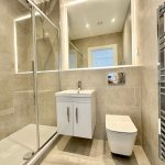 Modern bathroom with glass shower and vanity unit.