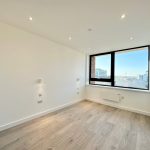 Empty room with wood flooring and large window.