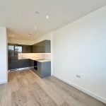 Modern kitchen with wooden flooring and white walls.